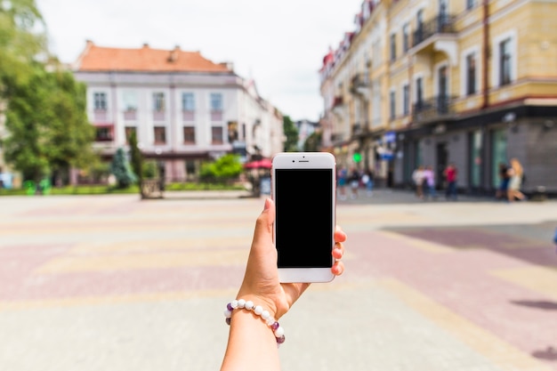 Main de femme tenant le téléphone portable avec écran blanc à l&#39;extérieur