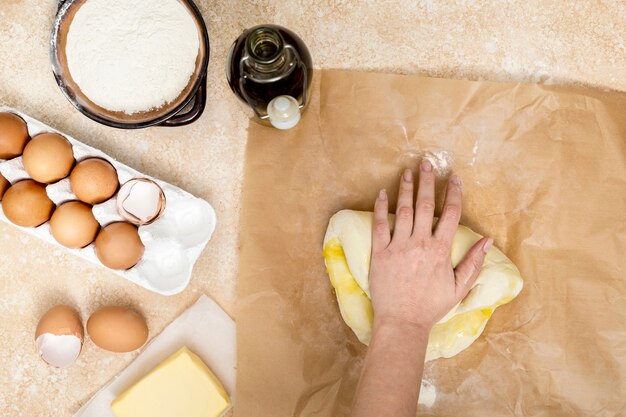 Main de femme en train de pétrir la pâte avec de l&#39;huile sur papier parchemin