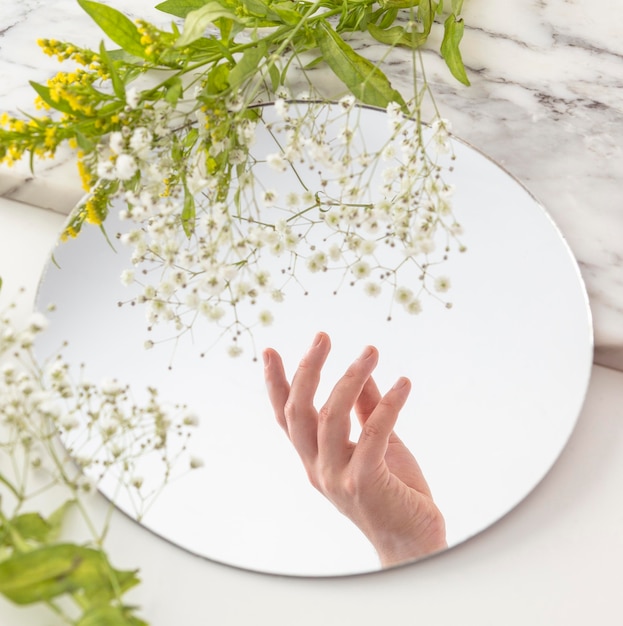 Photo gratuite main avec des fleurs en miroir