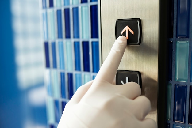 Photo gratuite main gantée appuyant sur un bouton d'ascenseur pour éviter la contamination par coronavirus