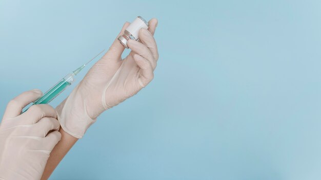 Main avec des gants tenant une seringue avec un vaccin et copiez l'espace