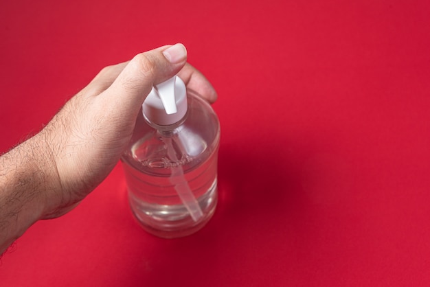 Main de l'homme dans un récipient avec du gel d'alcool sur le rouge