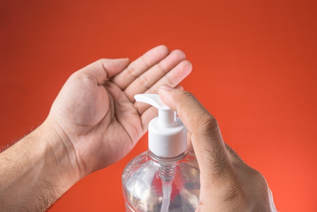 Photo gratuite main de l'homme dans un récipient avec du gel d'alcool sur le rouge