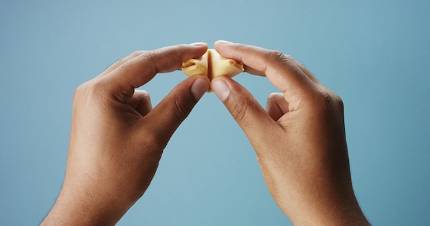 La main d'un homme de race mixte ouvre des biscuits de fortune avec un papier vide