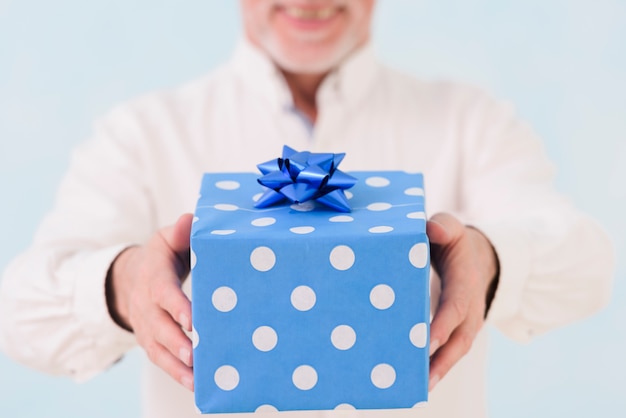 Main de l&#39;homme tenant une boîte cadeau d&#39;anniversaire enveloppé bleu