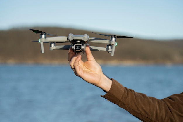 Main d'homme tenant un drone à l'extérieur