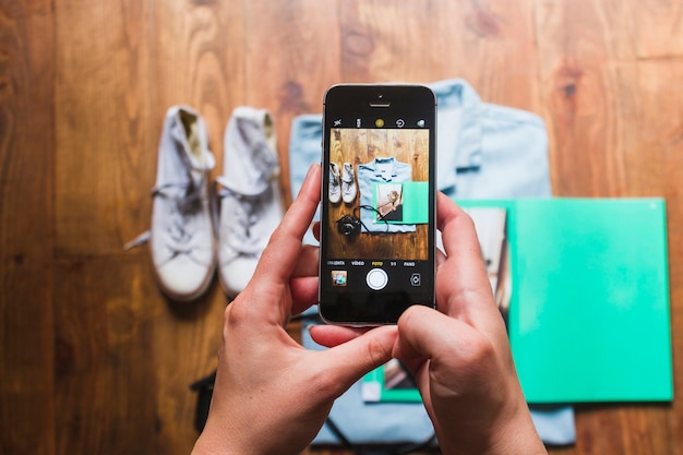 Main humaine prenant une photo d'accessoires personnels sur la table