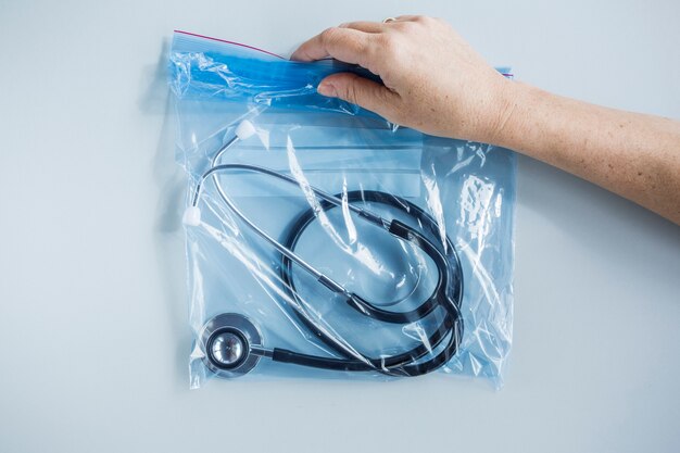 Main humaine tenant le sac en plastique de fermeture zip avec stéthoscope