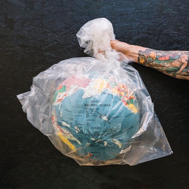 Photo gratuite main humaine tenant un sac en plastique avec globe