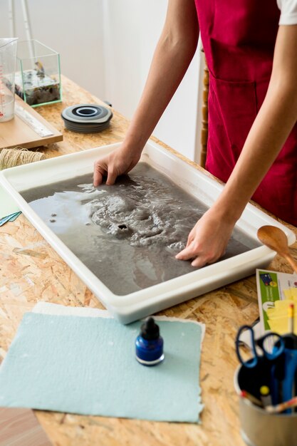 Main de la jeune fille faisant du papier dans l&#39;atelier