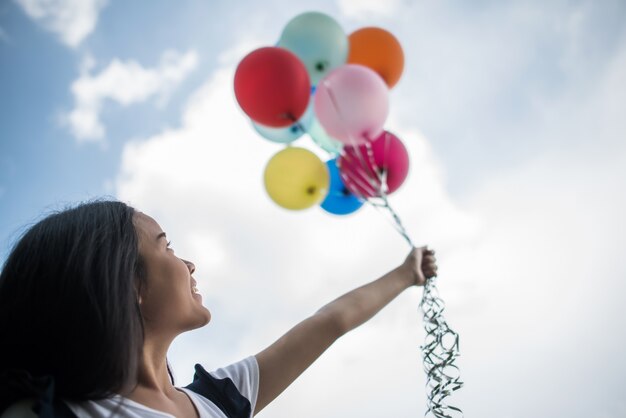 Main de jeune fille tenant des ballons colorés