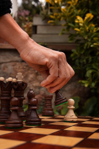 Photo gratuite main jouant aux échecs sur un plateau classique