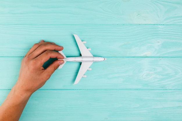Photo gratuite main avec jouet avion sur turquoise