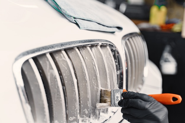 Main masculine avec éponge en mousse, lavage de voiture