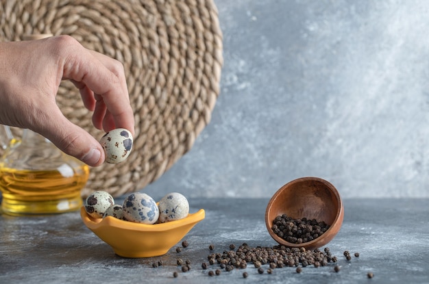 Main masculine prenant l'oeuf de caille du bol.