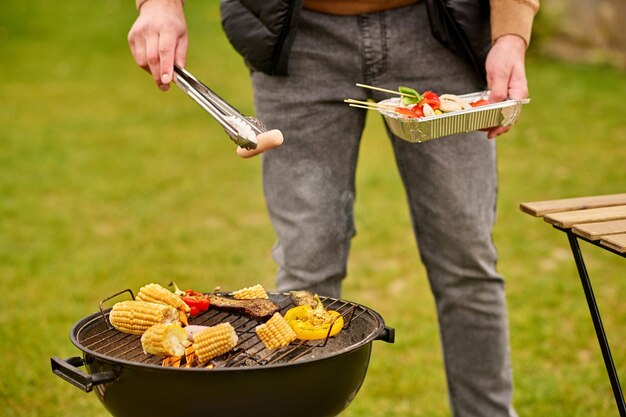 Main masculine tenant des pinces avec des saucisses au barbecue