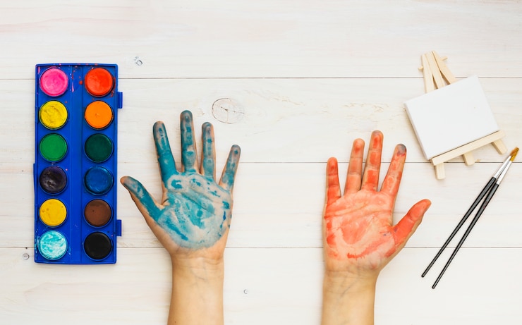 Photo gratuit main peinte et matériel de peinture sur table en bois