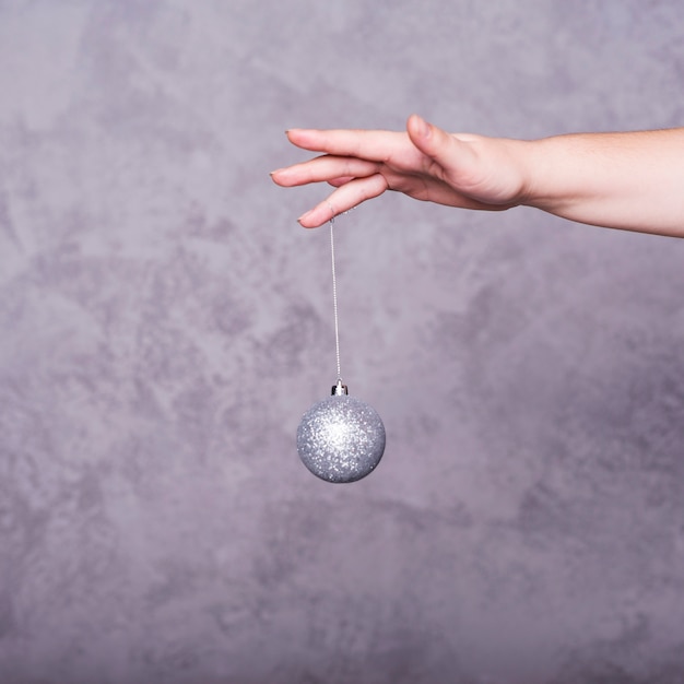 Photo gratuite main de la personne avec une boule de noël sur le fil