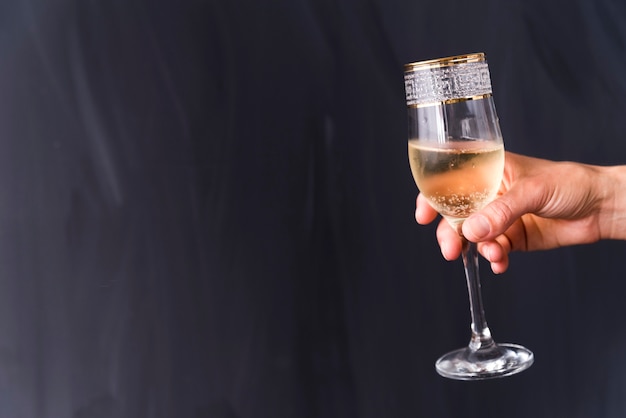 Main d'une personne tenant un verre de champagne élégant avec une bulle sur fond noir