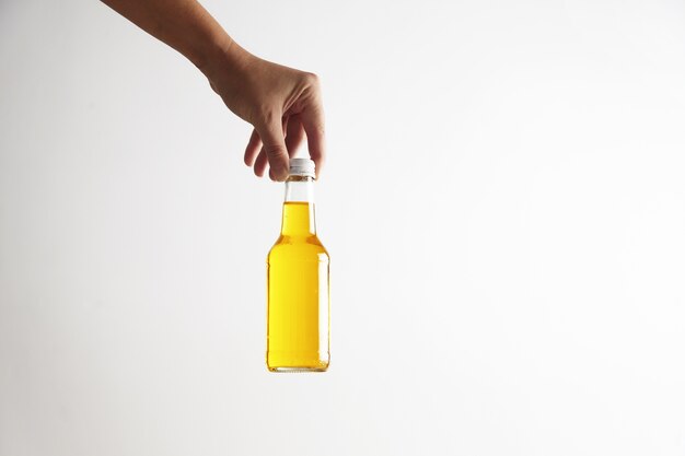 La main pose une bouteille en verre rustique fermée avec une délicieuse boisson froide à l'intérieur