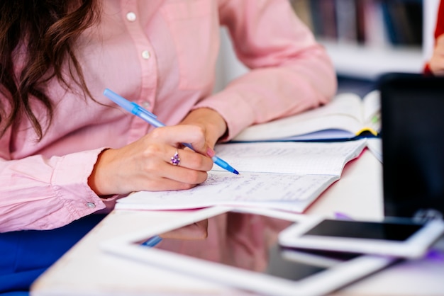 Main qui écrit dans le cahier à table