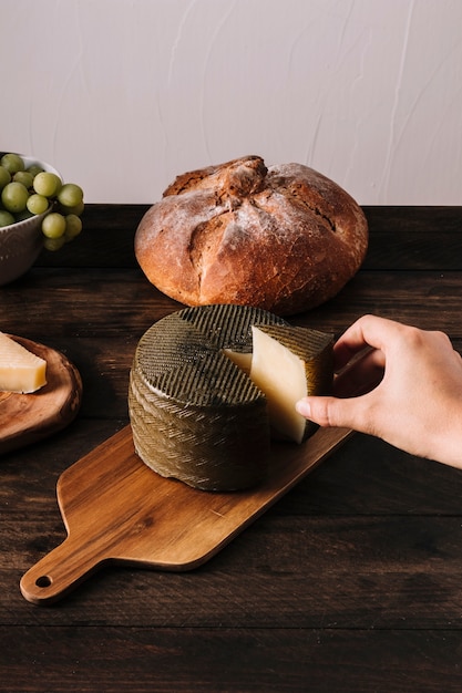 Main de récolte prenant du fromage de la planche à découper