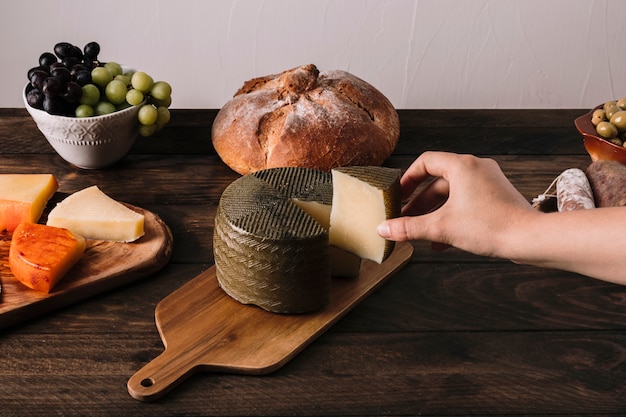 Main de récolte prenant du fromage près de la nourriture