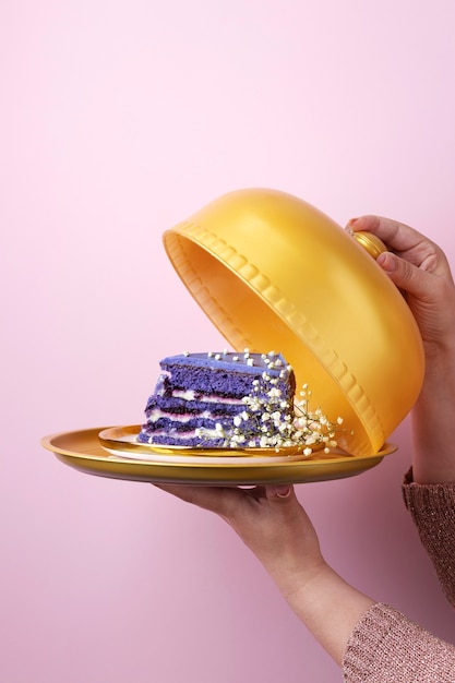 Main tenant une assiette dorée avec un gâteau et des fleurs