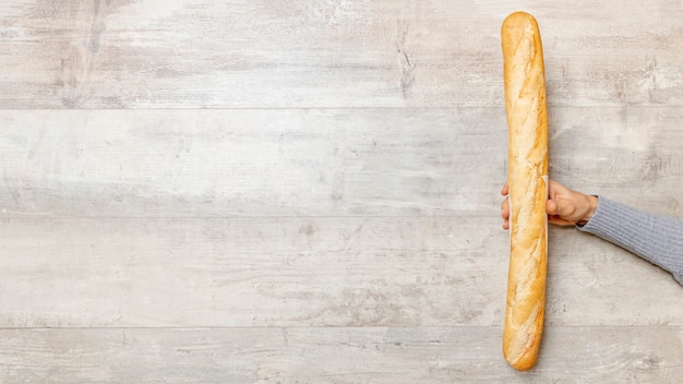 Main tenant une baguette de pain avec espace copie