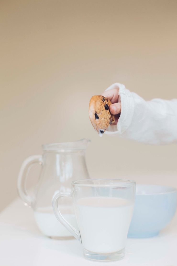 Photo gratuit main tenant un biscuit sur du lait