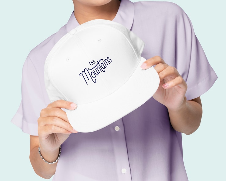 Photo gratuit main tenant une casquette de baseball blanche avec le logo des montagnes imprimé