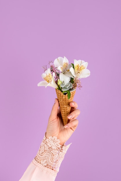 Main tenant un cornet de crème glacée avec des fleurs