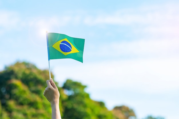 Main tenant le drapeau du brésil sur fond de ciel bleu. jour de l'indépendance de septembre et concepts de célébration heureuse