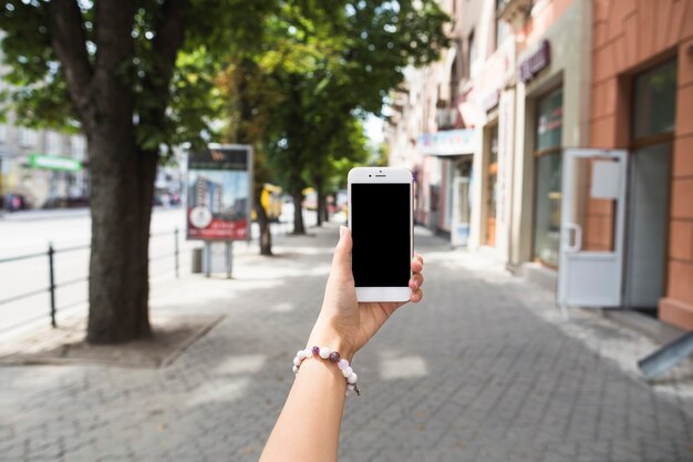 Main tenant mobile avec écran blanc à la rue