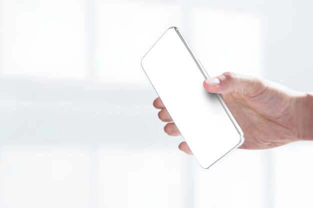 Main tenant un smartphone avec écran blanc
