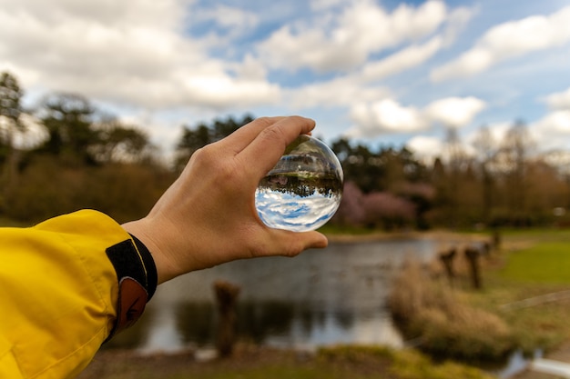 Main tenant une sphère de verre dans la nature