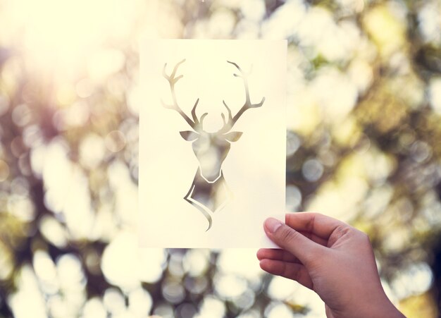 Main tenir le cerf avec des bois Sculpture en papier avec le fond de la nature