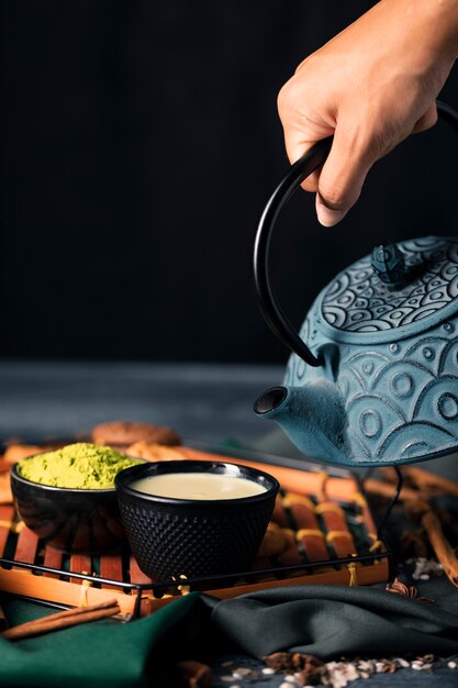 Main verser du thé matcha sur des tasses