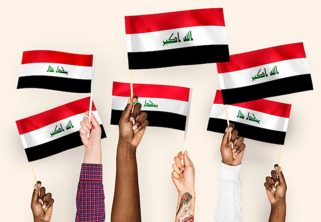 Photo gratuite mains agitant des drapeaux de l'irak