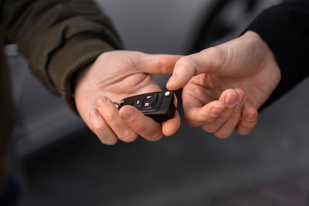 Photo gratuite mains à angle élevé tenant la clé de la voiture