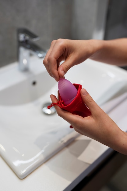 Mains à angle élevé tenant une coupe menstruelle