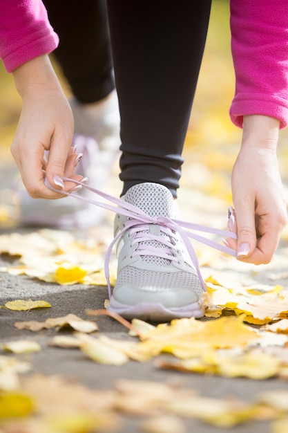 Photo gratuite mains attachant des chaussures aux chaussures sur le pavé d'automne