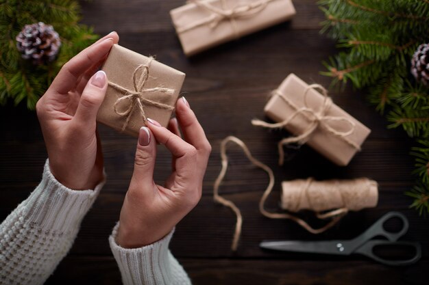 Mains attachant le noeud de chaîne de paquets cadeaux