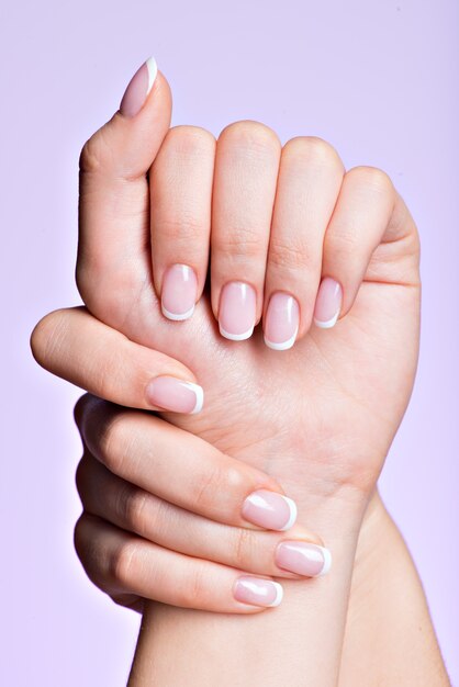 Les mains de la belle femme avec de beaux ongles après salon de manucure avec manucure française