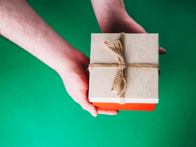 Mains avec boîte-cadeau sur vert