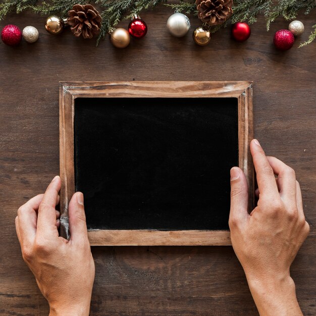 Mains avec cadre photo près de décorations de Noël