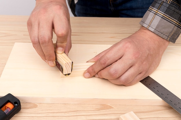 Mains de charpentier qualifiés travaillant avec des morceaux de bois