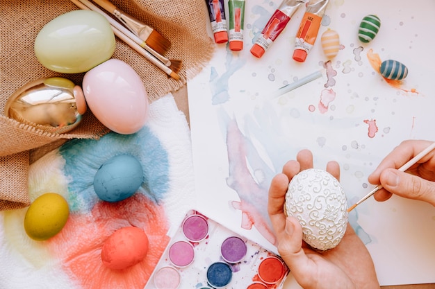 Mains colorant les oeufs de Pâques avec la brosse