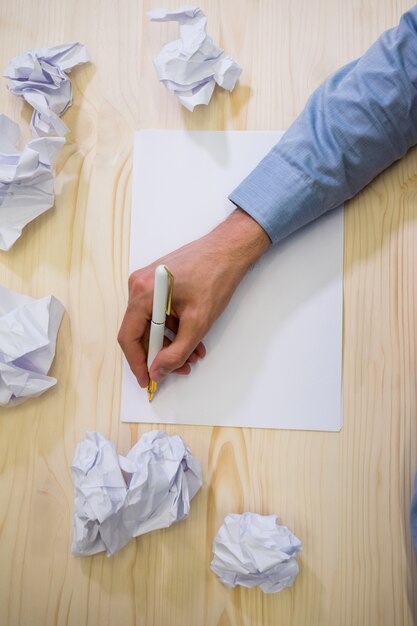 Mains de dirigeant d&#39;entreprise à écrire sur du papier blanc