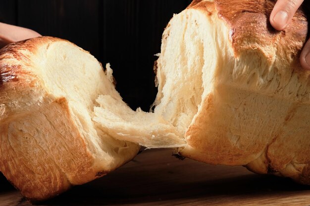 Les mains du boulanger cassant des petits pains briochés dans la moitié des petits pains briochés sucrés Concept de boulangerie brioche française traditionnelle Libre mise au point sélective